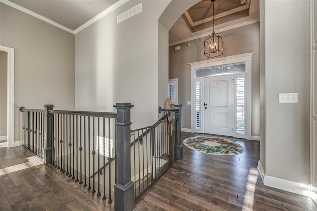 foyer entrance with crown molding, dark hardwood / wood-style flooring, and a notable chandelier