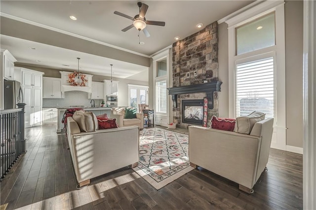 living room featuring a stone fireplace, ceiling fan, dark hardwood / wood-style flooring, and ornamental molding