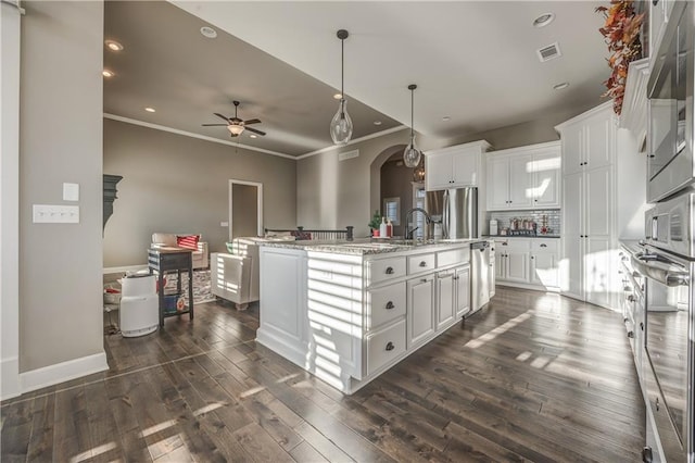 kitchen featuring white cabinets, an island with sink, pendant lighting, and appliances with stainless steel finishes