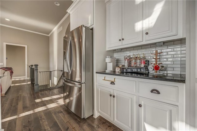 kitchen with white cabinets, stainless steel fridge, decorative backsplash, and dark wood-type flooring