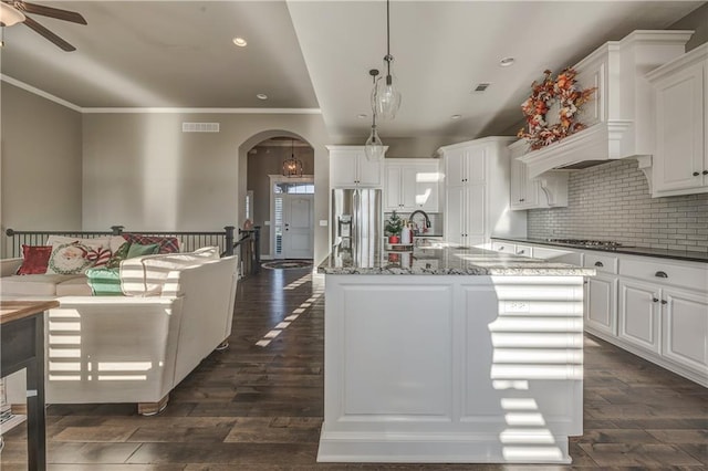 kitchen featuring pendant lighting, a large island with sink, white cabinets, appliances with stainless steel finishes, and dark hardwood / wood-style flooring