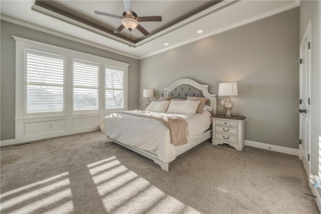 carpeted bedroom with ceiling fan, a raised ceiling, and crown molding