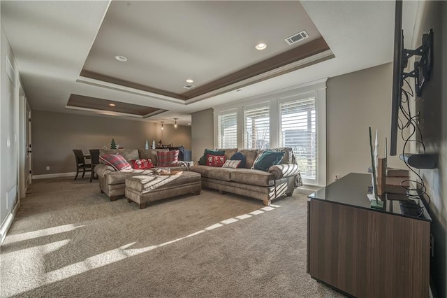 carpeted living room with a raised ceiling and ornamental molding