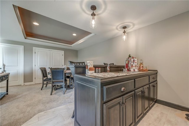 kitchen featuring light carpet, a raised ceiling, sink, dark brown cabinetry, and kitchen peninsula