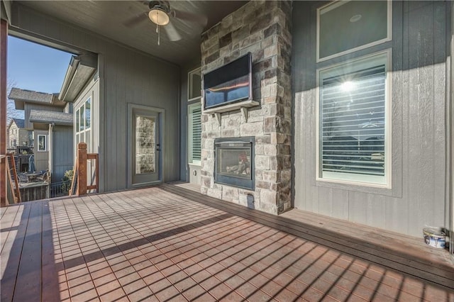 wooden deck with ceiling fan and a fireplace