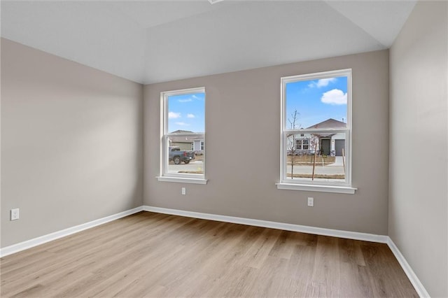 spare room with light hardwood / wood-style flooring and lofted ceiling