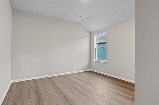 spare room featuring vaulted ceiling and light wood-type flooring