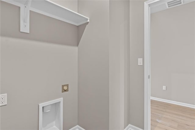 laundry room featuring electric dryer hookup and light hardwood / wood-style flooring