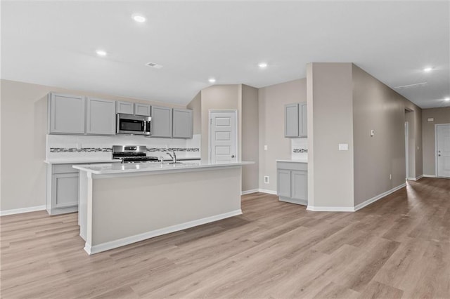 kitchen featuring stainless steel appliances, gray cabinets, and a kitchen island with sink