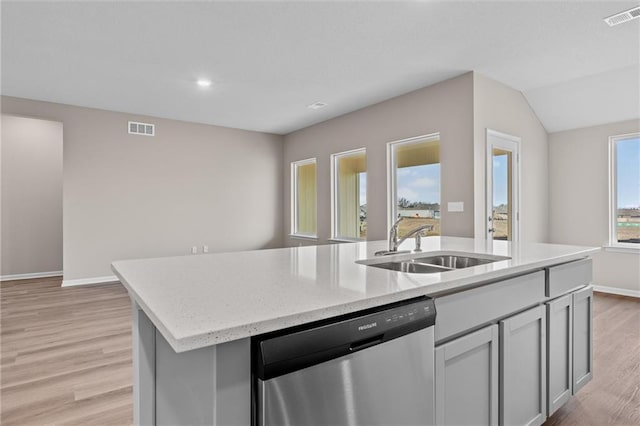 kitchen with stainless steel dishwasher, light hardwood / wood-style floors, a kitchen island with sink, sink, and gray cabinets