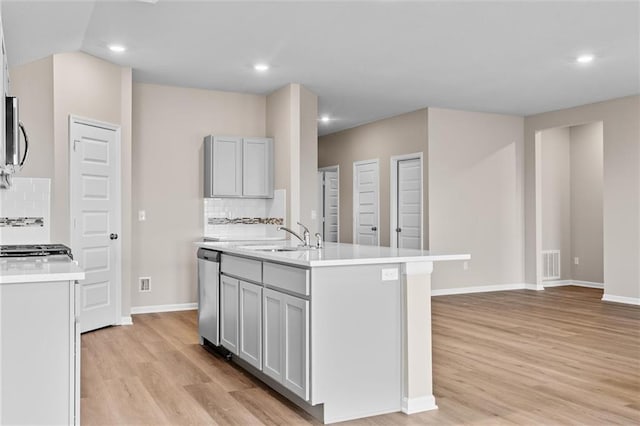 kitchen featuring a center island with sink, stainless steel dishwasher, tasteful backsplash, and sink