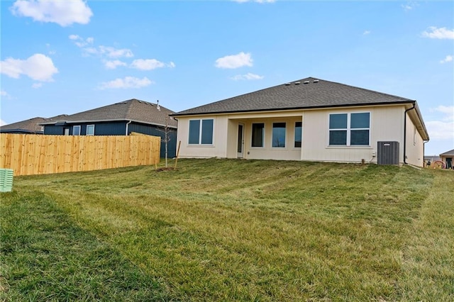 rear view of property featuring a lawn and central AC unit