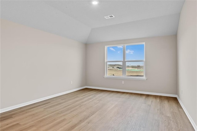 empty room with light hardwood / wood-style flooring and vaulted ceiling