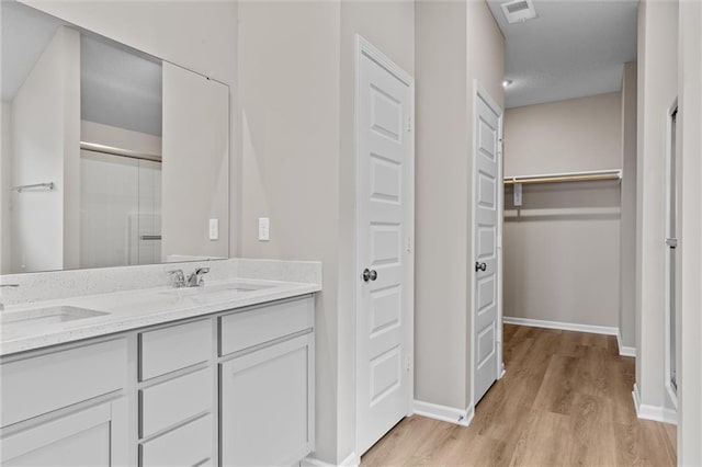 bathroom featuring wood-type flooring, vanity, and walk in shower