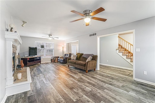 living room featuring ceiling fan, a fireplace, and dark hardwood / wood-style floors