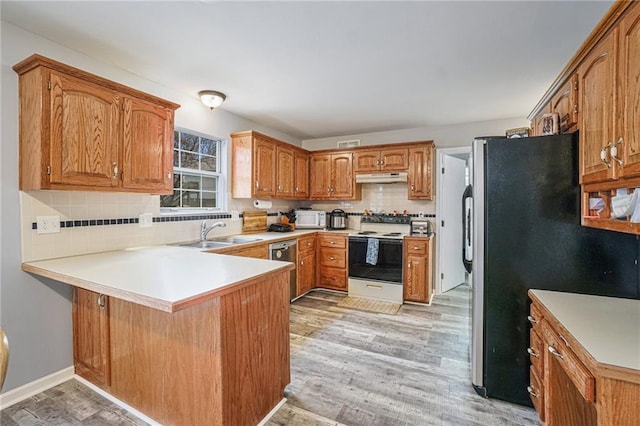 kitchen featuring kitchen peninsula, sink, stainless steel appliances, and light hardwood / wood-style flooring