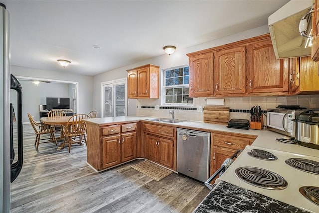 kitchen featuring hardwood / wood-style floors, sink, appliances with stainless steel finishes, tasteful backsplash, and kitchen peninsula