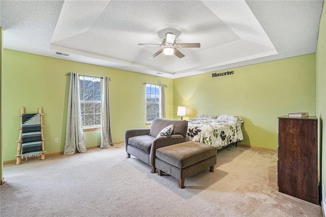 carpeted bedroom with a raised ceiling, ceiling fan, and a textured ceiling