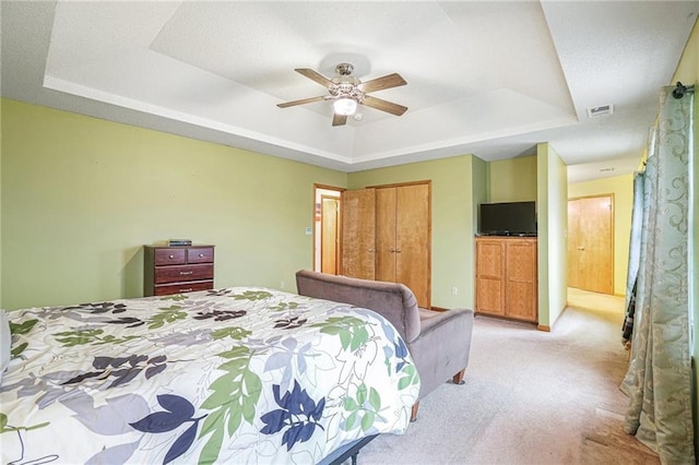 carpeted bedroom featuring a raised ceiling and ceiling fan