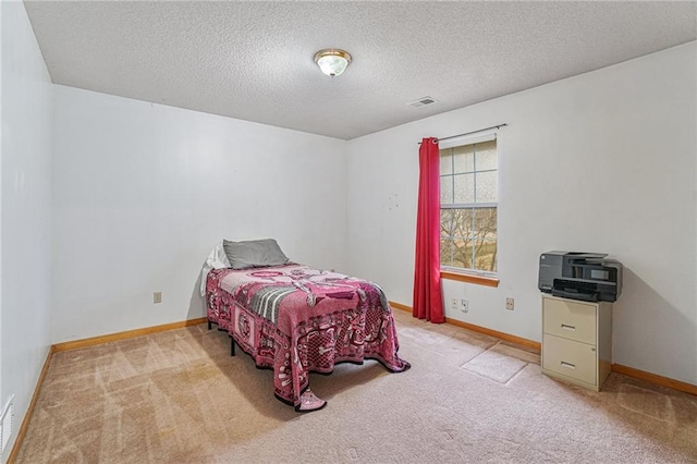 bedroom with light colored carpet and a textured ceiling