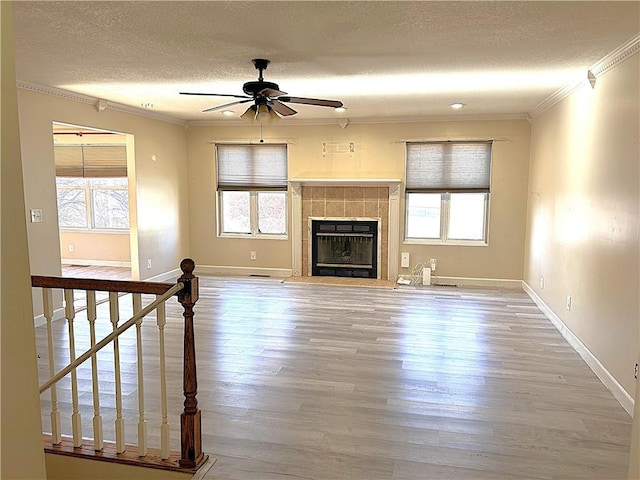 unfurnished living room featuring a fireplace, wood-type flooring, a textured ceiling, and ceiling fan