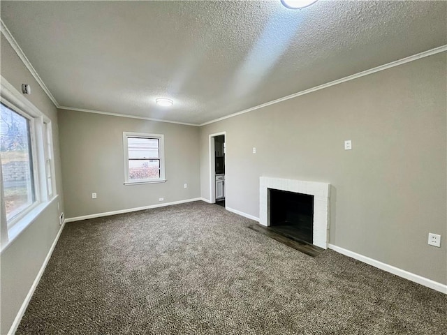 unfurnished living room featuring a brick fireplace, ornamental molding, a textured ceiling, and dark colored carpet