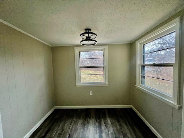 empty room featuring a textured ceiling, crown molding, and dark wood-type flooring