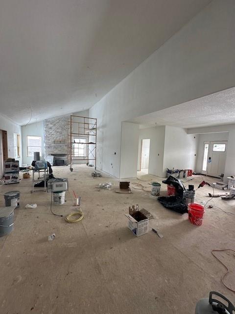 misc room with high vaulted ceiling and a fireplace with raised hearth