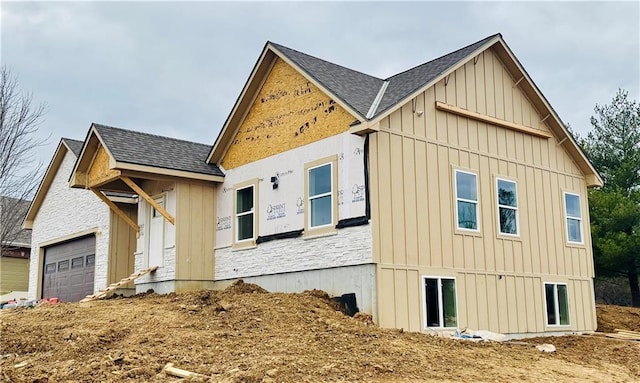 view of side of home featuring a garage, roof with shingles, and board and batten siding