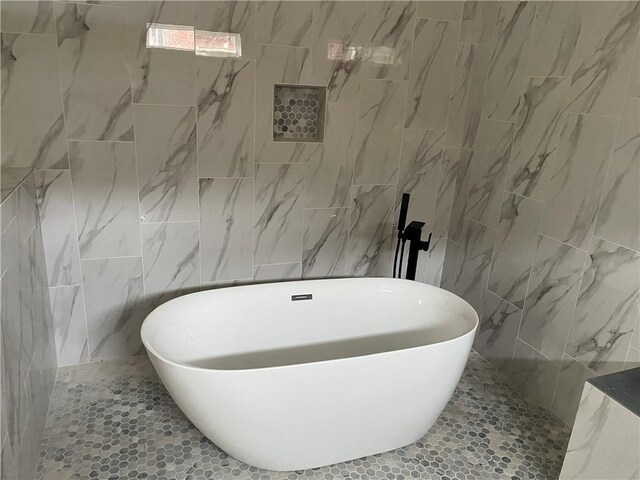 bathroom featuring a soaking tub and tile walls