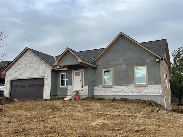 view of front of house featuring stucco siding, stone siding, a shingled roof, and a garage