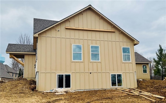 rear view of property with board and batten siding and a shingled roof