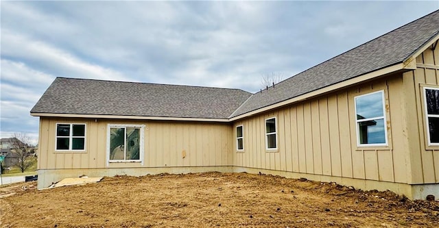 back of property with board and batten siding and a shingled roof