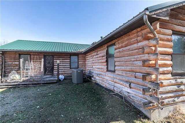 back of house with metal roof, central AC unit, and a lawn