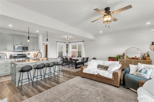 living room with light hardwood / wood-style flooring, ceiling fan, and sink