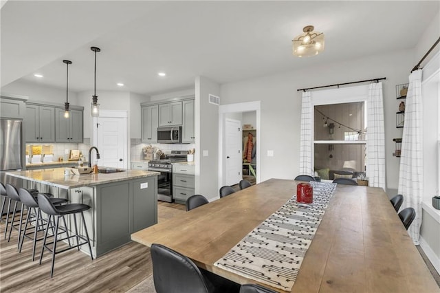 kitchen with appliances with stainless steel finishes, a kitchen breakfast bar, sink, pendant lighting, and gray cabinets