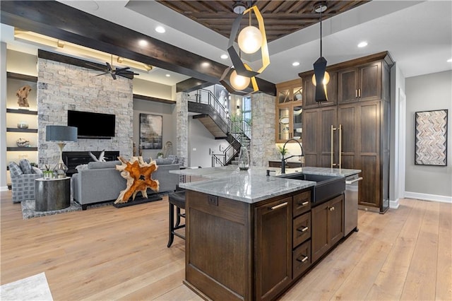 21359 W 93rd Ct, Lenexa, KS 66220 - kitchen featuring a sink, baseboards, dark brown cabinetry, a kitchen breakfast bar, and light wood finished floors