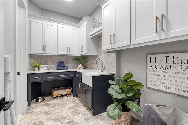 21359 W 93rd Ct, Lenexa, KS 66220 - kitchen with white cabinetry, a sink, decorative backsplash, blue cabinetry, and light stone finish floors