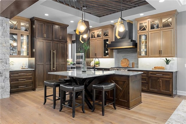 21359 W 93rd Ct, Lenexa, KS 66220 - kitchen with wall chimney exhaust hood, stainless steel microwave, a center island with sink, a breakfast bar area, and recessed lighting