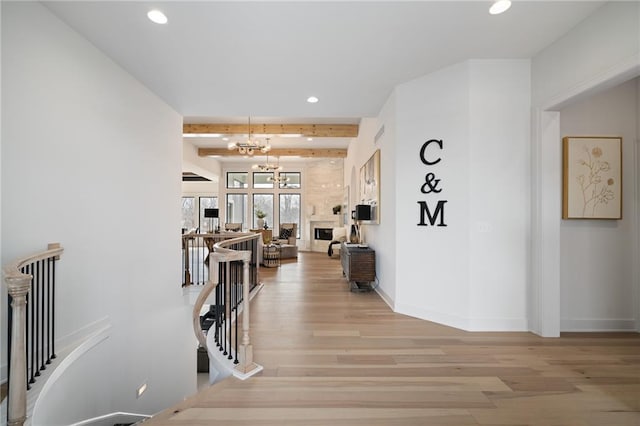 corridor featuring a chandelier, beam ceiling, and light hardwood / wood-style flooring