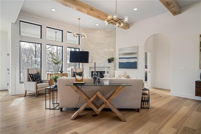 living room featuring light hardwood / wood-style floors, a chandelier, and beamed ceiling