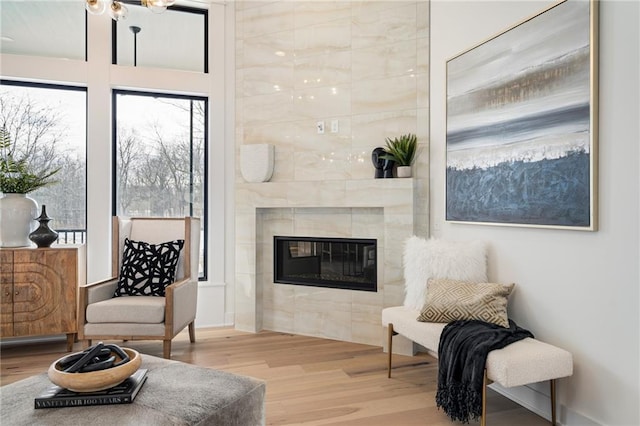 sitting room with a tile fireplace and light wood-type flooring