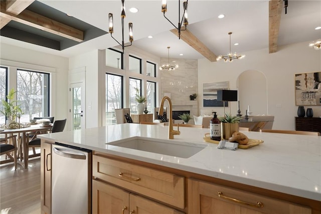 kitchen with decorative light fixtures, sink, a chandelier, light stone counters, and a tile fireplace