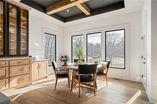 dining area with beamed ceiling and light hardwood / wood-style flooring