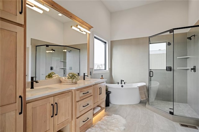 bathroom with vanity and shower with separate bathtub