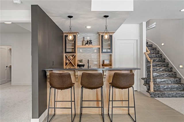 bar featuring light carpet, sink, and pendant lighting