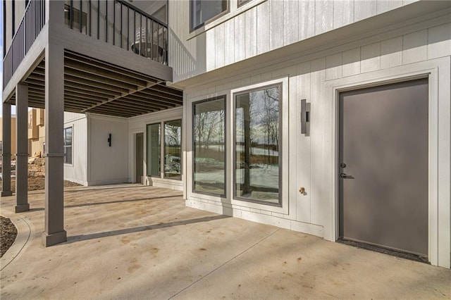 view of exterior entry featuring a patio area and a balcony