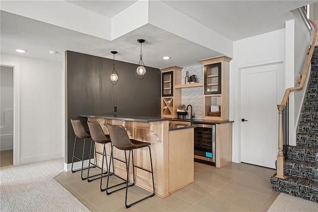 kitchen featuring pendant lighting, kitchen peninsula, a kitchen bar, light tile patterned floors, and beverage cooler