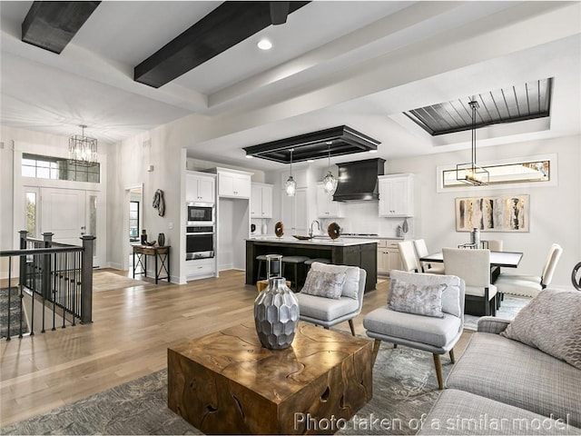 living room with an inviting chandelier, sink, and light hardwood / wood-style floors