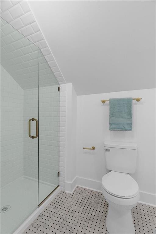 bathroom with toilet, vaulted ceiling, a shower stall, and baseboards